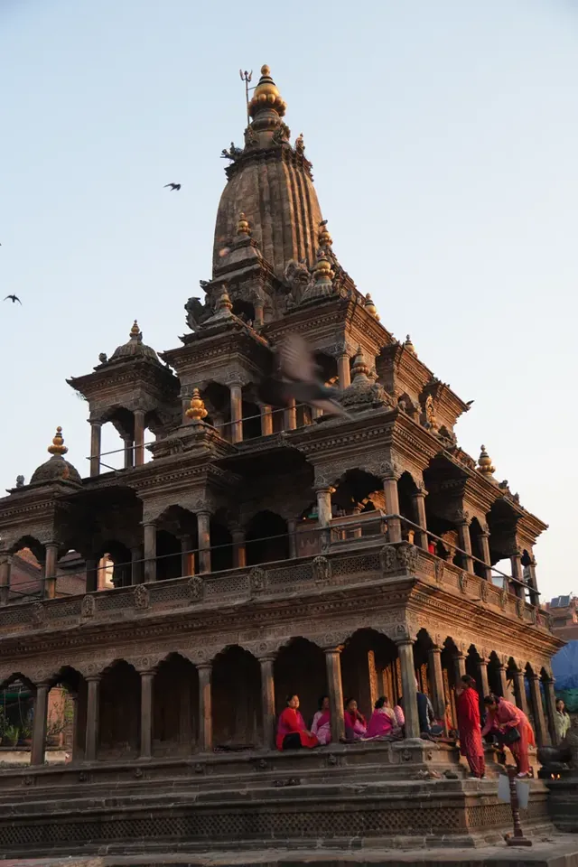 Krishna Mandir in Patan, a stone temple with a tall spire and carved arches, lit by soft evening light