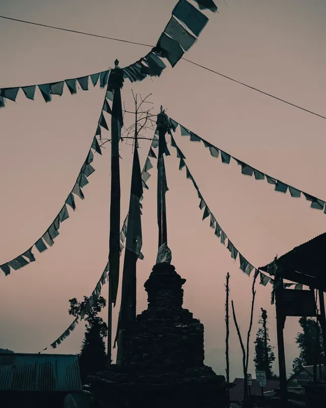 Silhouette of a stepped stupa and strings of prayer flags against a hazy pink dusk sky, Panch Pokhari